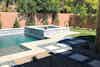 a pool with a stone wall and a fence