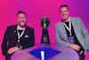 two men sitting at a table with a trophy
